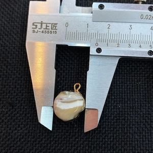 Macro shot of a 15mm irregular natural shell pendant measured with professional calipers