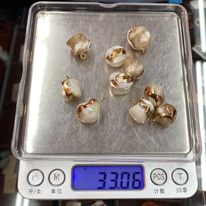 Bulk set of irregular natural shell pendants with gold trim on a digital scale 33.06g