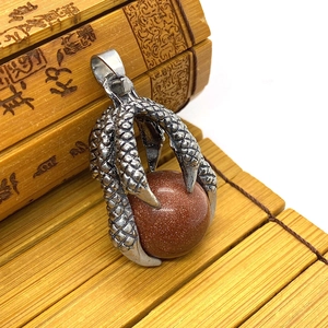Close-up of a silver dragon claw pendant holding a round red goldstone gem for DIY jewelry