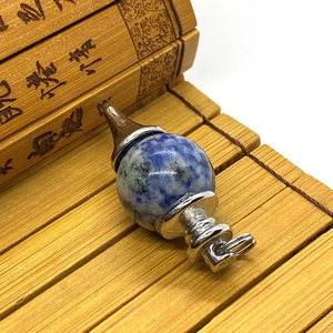 Macro shot of blue and white stone pendulum pendant on a natural bamboo background