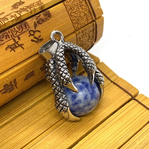 Macro shot of retro dragon claw pendant with blue stone on vintage bamboo scroll