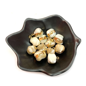 Irregular natural shell pendants with gold foil edges and hanging rings in a black dish