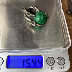 Macro shot of malachite green stone ball held by vintage silver dragon claws on a scale