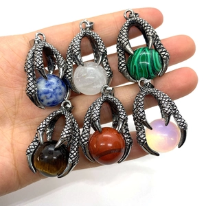 Dragon claw pendant with natural stone spheres in various colors, held for size scale
