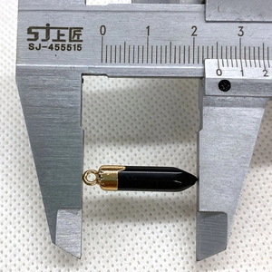Macro view of 22mm black hexagonal bullet pendant with gold bail and digital caliper measurement