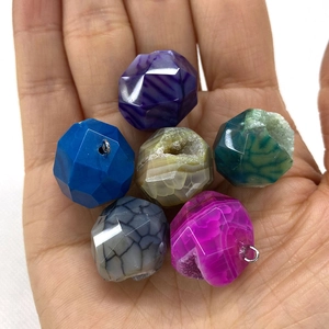 Faceted natural stone pendants in various colors shown held by hand for size reference