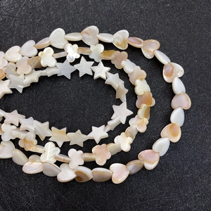 Macro detail of heart and flower-shaped natural freshwater shell beads for DIY jewelry