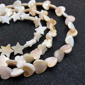 Macro shot of natural mother of pearl shell beads in heart, star, and flower shapes