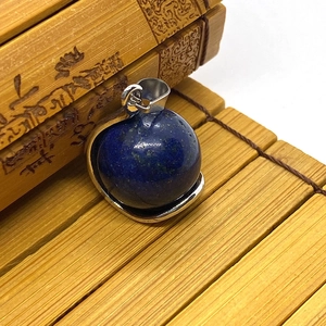 Macro shot of sphere lapis lazuli pendant with gold flecks on traditional bamboo mat