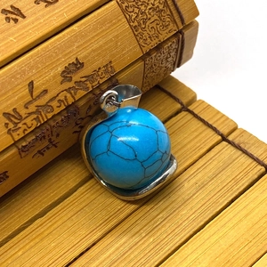 Macro shot of blue turquoise sphere pendant with silver metal frame on bamboo mat