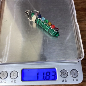 Detailed macro view showing a 11.83g hexagonal stone pendant with seven chakra gems