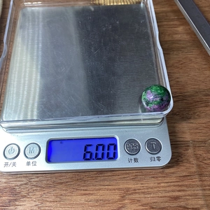 Detalle de una cuenta redonda de rubí zoisita de 6,00g en una báscula digital