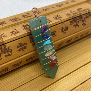 Macro shot of green aventurine stone pendant with copper wire wrap and chakra crystals
