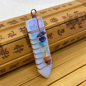 Macro detail of hexagonal opal pendant with wire-wrapped seven chakra natural gemstones