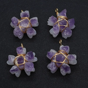 Set of four star-shaped purple amethyst pendants with gold wire wrapping on black surface