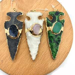 Drie conische hangers van natuursteen met gouden plating op een houten plateau