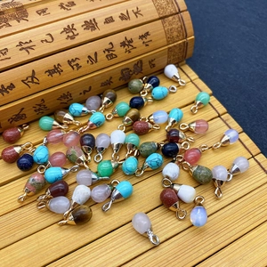 Waterdrop-shaped natural stone pendants with gold and silver loops on bamboo background