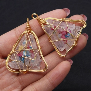 Detail of handmade gold wire-wrapped triangular white crystal pendant with colored stones