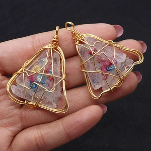 Close-up of handmade gold wire-wrapped triangular natural stone pendants being held