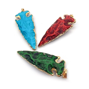 Detail van drie hars hangers in blauw, rood en groen met een gouden metalen rand