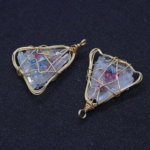 Detailed close-up of handmade white crystal triangle pendants with gold wire wrapping