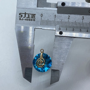 Detail shot showing 15mm diameter measurement of the blue crystal pendant with a gold rose motif