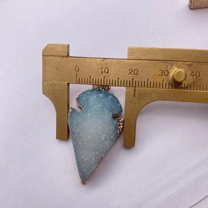 Primer plano de colgante de flecha de cristal azul con borde dorado y escala graduada