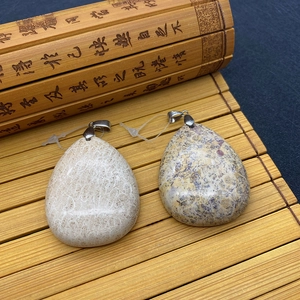 Pendentifs gouttes en pierre naturelle crème et jaune sur un tapis de bambou décoratif