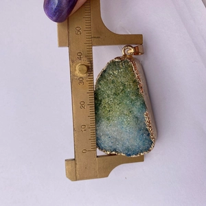 Macro shot measuring blue and green druzy stone pendant with a vernier caliper