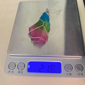 Regenboog kristallen hanger omwikkeld met zilverdraad op een digitale weegschaal