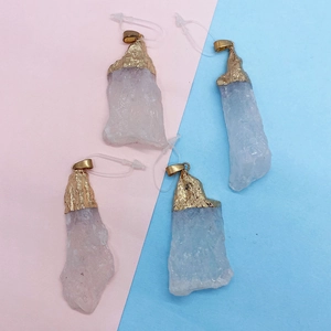 Quattro pendenti in cristallo bianco naturale con cappucci dorati su sfondo rosa e blu