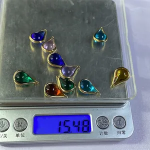 Détail de pendentifs gouttes en cristal sur une balance affichant un poids de 15,48g