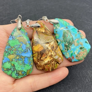 Trois pendentifs gouttes en pierre naturelle turquoise avec fermoirs argentés sur gris