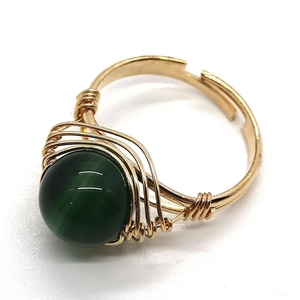 Detailed view of handmade gold wire-wrapped ring with green cat eye gemstone bead