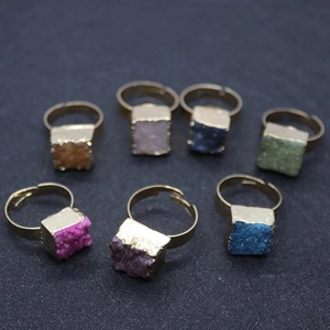 Vue macro de sept bagues carrées en druzy multicolore montées sur un alliage doré élégant