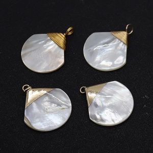 Vue macro de quatre pendentifs en nacre naturelle en forme de goutte et fil doré