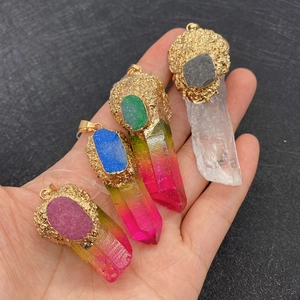 Pendentifs en pierre de cristal naturel avec bordure dorée tenus à la main
