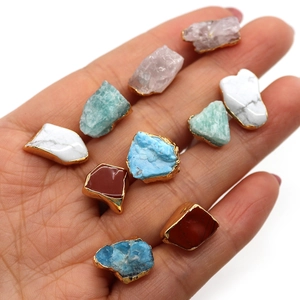 Natural raw crystal pendants with gold edges in various colors held in hand