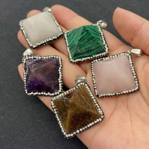 Detalle de colgantes piramidales de piedra natural con bordes de strass en la mano