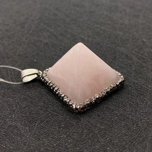 Detalle de un colgante de pirámide de cuarzo rosa con base plateada y cristales