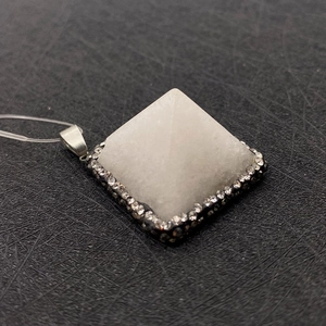 Detalle del colgante pirámide de cristal blanco con pedrería y base de metal negro