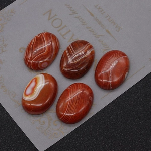 Polished red striped agate oval cabochons displayed on a grey card with stone texture