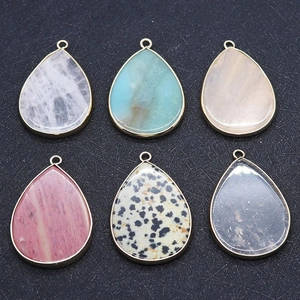 Macro detail of teardrop gemstone pendants with gold plated edges in various natural stones