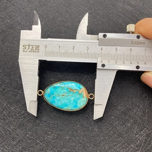 Détail du connecteur ovale en turquoise avec plaquage or et échelle de mesure