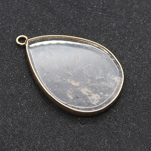 Natural teardrop crystal pendant with gold edge and brown inclusions on black background