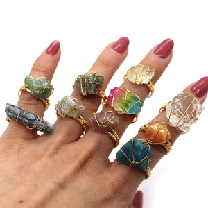 Dettaglio di anelli boho fatti a mano con filo d'oro avvolto intorno a vari cristalli naturali