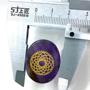 Macro view of purple oval stone with golden chakra symbol being measured by a caliper