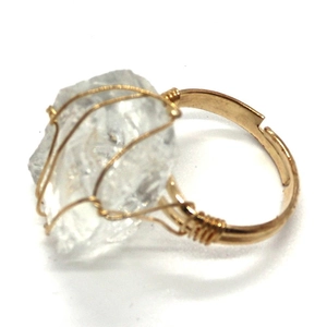 Dettaglio macro dell'anello regolabile fatto a mano in filo dorato e cristallo naturale