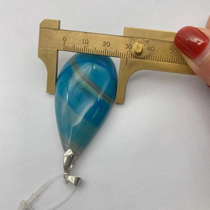 Misurazione di un ciondolo a goccia in agata blu da 30mm con un calibro in ottone