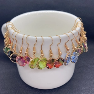 Macro detail of faceted gradient crystal pendants with gold hooks on a white display cup